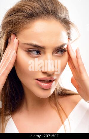 Pretty woman holding herself for the face and stretching up the skin to make her look younger. Big lips, blue eyes looking away. Volume blonde hairs Stock Photo