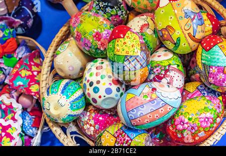 Wooden Easter eggs with bright drawings lie in a wicker basket. Stock Photo