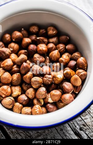 Peeled hazelnuts in bowl on old wooden table. Stock Photo