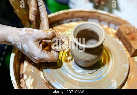 Professional potter makes a pot on a pottery wheel. Hands of a potter. Stock Photo