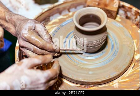 Professional potter makes a pot on a pottery wheel and teaches a pupil. Hands of a potter. Stock Photo