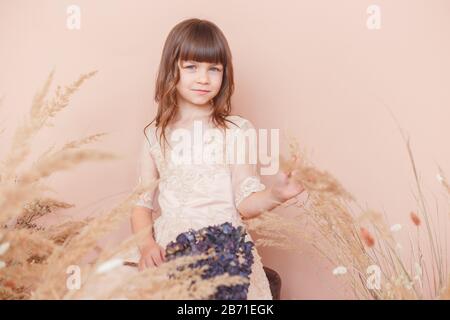 Young model girl in beige dress smiling on pastel color background Stock Photo