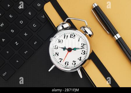 Metal vintage alarm clock on black keyboard. Laptop work and planning flat lay concept Stock Photo