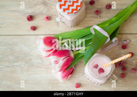 Pink latte healthy beverage trendy beetroot latte and raspberry smoothie, with tulips flowers. Flat lay image Stock Photo