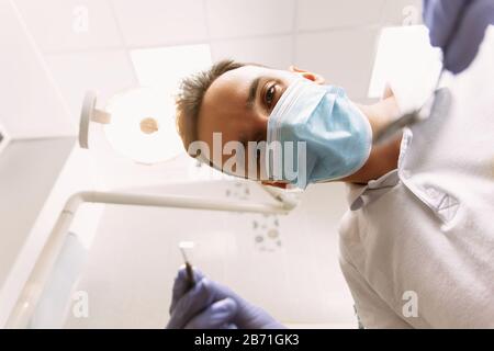 Dentist Holding Dental Tools. Professional dental doctor is working in office. Inspection at the Dentist from the point of view of the patient. The dentist holds tools in order to examine the patient. Stock Photo