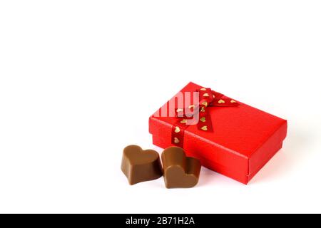 Two chocolate candies in a form of heart and a small red gift box on the white background isolated closeup. Holiday greeting , Valentine's day, Mom's Stock Photo