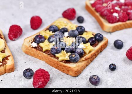 Slice of spelt toast bread topped with healthy blueberry and banana fruits and puffed quinoa grains Stock Photo