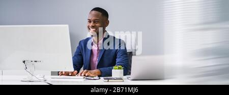 African Businessman Banner Using Computer In Office Stock Photo