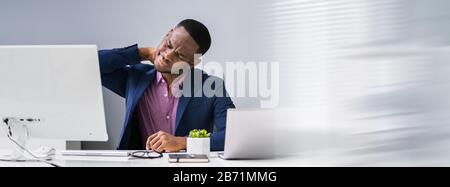 Businessman Suffering From Neck Pain At Desk Stock Photo