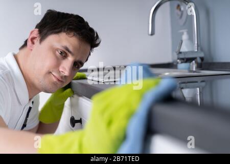 Young Cleaner Man Wearing Apron Cleaning Dirty Kitchen Worktop Stock Photo