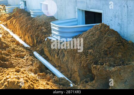 Plastic piping and a rainpipe against and around the a drain pipe in ground house Stock Photo