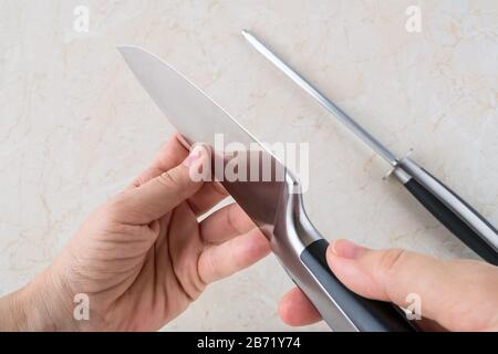 https://l450v.alamy.com/450v/2b71y74/woman-hands-checking-the-blade-of-professional-chef-knife-after-using-the-sharpening-steel-kitchen-utensils-of-high-carbon-molybdenum-vanadium-steel-2b71y74.jpg