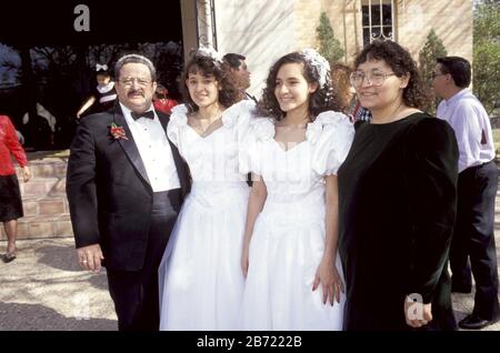 Austin Texas USA: 15-year-old Hispanic twin sisters, celebrating their quinceaneras together, pose with their parents after their church ceremony. ©Bob Daemmrich / Stock Photo