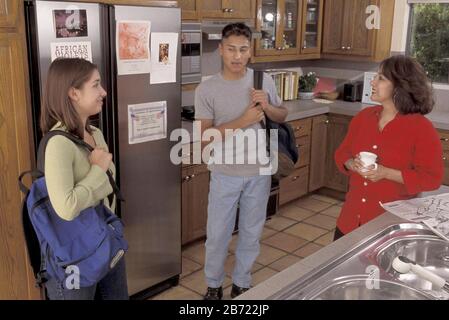 Austin Texas USA: Hispanic teen siblings talk to their mother in the morning at their home before leaving for school. MR ©Bob Daemmrich Stock Photo