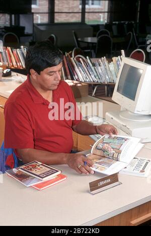 Austin, Texas USA: Male librarian working at his desk in elementary school library. ©Bob Daemmrich Stock Photo