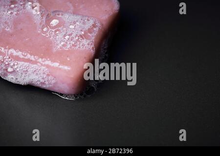 Closeup on a foamy pink soap bar on a dark background Stock Photo