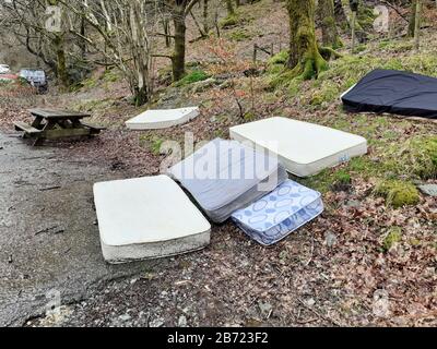 Mattreses fly tipped and illegally dumped in a car park at White moss, near Ambleside, Lake District, UK. Stock Photo