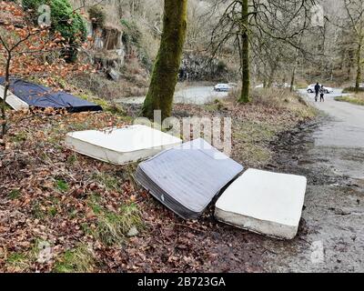 Mattreses fly tipped and illegally dumped in a car park at White moss, near Ambleside, Lake District, UK. Stock Photo