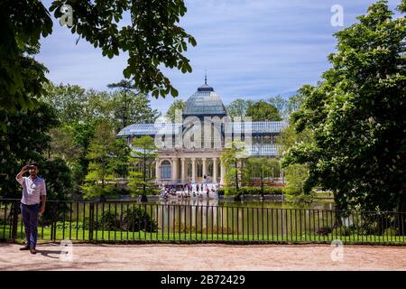 MADRID, SPAIN - MAY, 2018: Tourists taking a selfie in front of the beautiful Palacio de Cristal a conservatory located in El Retiro Park built in 188 Stock Photo