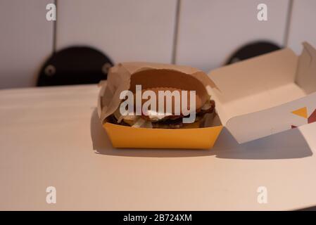 Hamburger in a take away container on table against white background. Hamburger on a white table in a box. Stock Photo