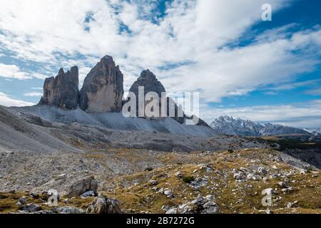 Striking view of Three Chimney rock formations found in Italian Dolomites. Interesting, partly sunny skies provide mottled shade on foreground Stock Photo