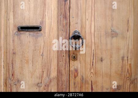 Elegant natural timber door with stylish door knocker and a mail box slot. Stock Photo