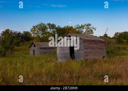 Old abandoned farm buildings that have been forgotten to time. These buildings were built by the first farming settlers of the Saskatchewan prairies Stock Photo