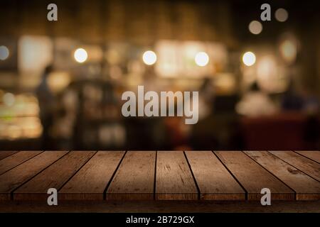 Wood table top on blur bokeh coffee shop or cafe restaurant background. Can be used for display or montage your products. Stock Photo