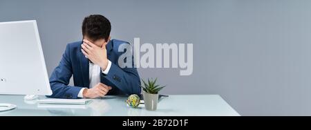 Man Suffering From Headache Working In Office Stock Photo