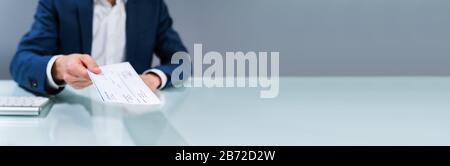 Close-up Of A Human Hand Giving Cheque On Desk Stock Photo