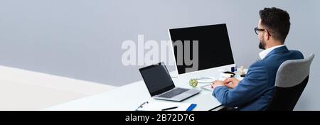 Close-up Of A Businessman Using Computer With Blank Screen At Workplace Stock Photo