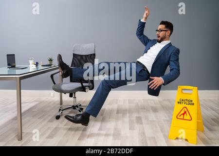 Businessman Falling On Slippery Floor At Workplace Stock Photo