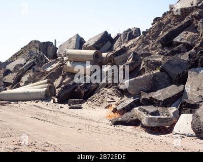 Wall of Asphalt and Concrete Pavement and Roadbed, Concrete Sewer Pipes, and Parking Lot Debris, Concrete Curbing, at Road Demolition Site Stock Photo