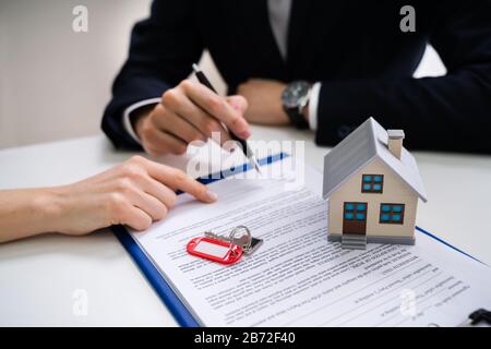 Close-up Of A Person's Hand Signing Contract With Keys On It Stock ...