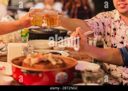 Short in low light man clinking glasses with alcohol celebrating family dinner. Stock Photo