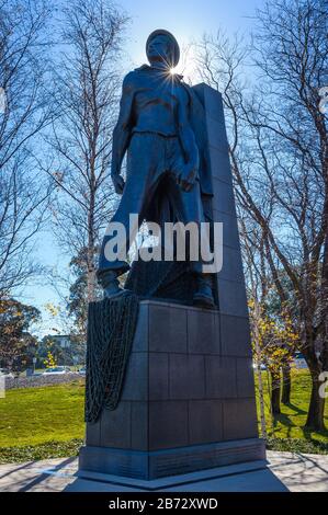 Upright, bronze lone soldier statue, with sun spike over his left shoulder commemorating the contribution of all Australian soldiers. Stock Photo