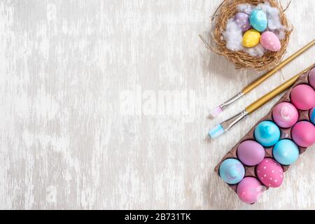 Home made painting easter eggs lay flat concept image on white wooden table top - copy space for text. Stock Photo