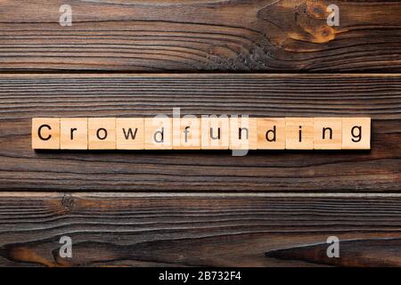 CROWDFUNDING word written on wood block. CROWDFUNDING text on wooden table for your desing, concept. Stock Photo