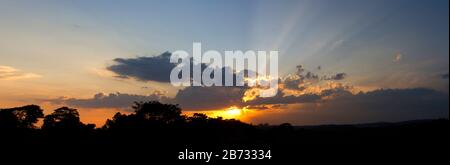 The sun sets over the Kibale National Park hills. The park is gradually becoming isolated and surrounded in uncontrolled habitat degradation Stock Photo