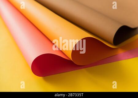 Pink and orange papers rolled together over yellow color paper. Papers for creative craft and design in school. Stock Photo