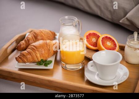 Breakfast in bed with orange fruits and pastries on a tray close up Stock Photo