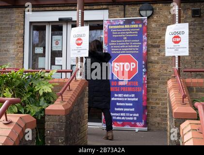 Berkhamsted, Hertfordshire, UK. 13th March, 2020. The NHS in England has given signage to Doctor’s surgeries warning against patients entering, if they think that they have the symptoms of Coronavirus. A surgery in Berkhamsted, Hertfordshire displays signs outside the entrance. Photo: ©  David Levenson/Alamy Live News Stock Photo
