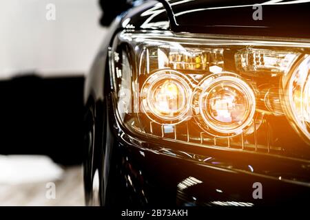 Headlight lamp of the new black luxury car, Close up detail on one of the LED headlights with flare of modern car. Automobile business. Stock Photo