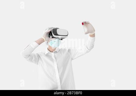 Young woman doctor in medical mask and test tube doing research in laboratory. Covid-19 Stock Photo