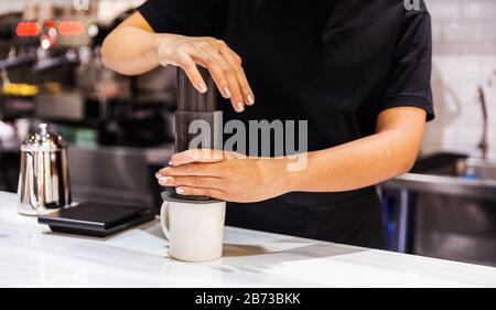 https://l450v.alamy.com/450v/2b73bkk/aero-press-system-coffee-preparation-method-woman-barista-in-a-black-t-shirt-press-aeropress-to-fill-a-glass-with-espresso-coffee-2b73bkk.jpg