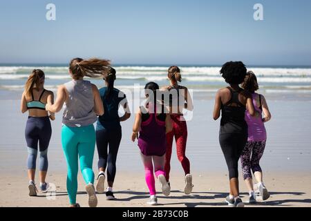 Rear view of women running at the beach Stock Photo
