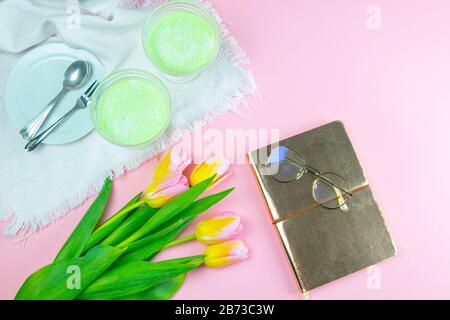 Colorful pinc and yellow tulip with notebook and eyeglasses flat lay isolated on pinc background top view. Spring flower. Womans day, mothers day Stock Photo