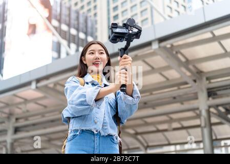 Smiling beautiful Asian woman tourist travel vlogger taking selfie video in the city Stock Photo