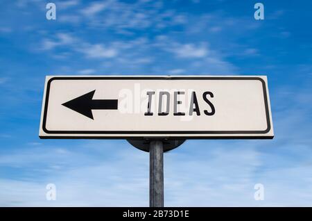 Ideas white road sign with arrow on blue sky background. One way road sign with copy space. Arrow on a pole pointing in one direction. Stock Photo