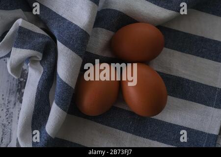 Three brown eggs on the striped napkin,top view. Stock Photo